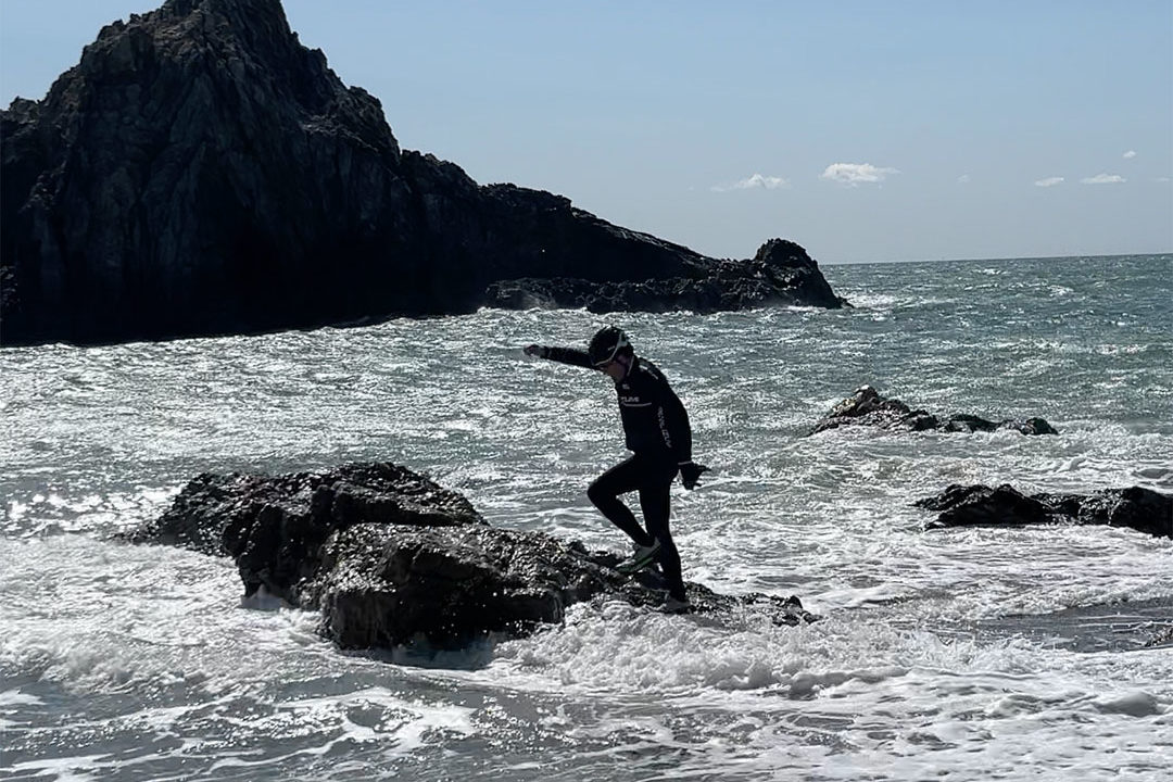 海岸の岩の上を慎重に歩く部員